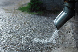 Rain water flowing from a metal downspout during a heavy rain. concept of protection against heavy rains.