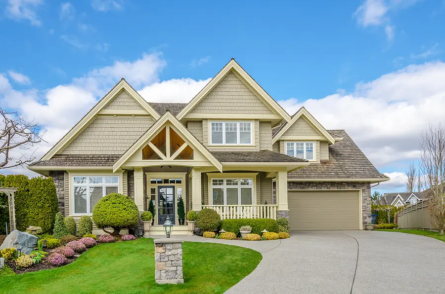 Luxury house with a two-car garage and beautiful landscaping on a sunny day. Home exterior.